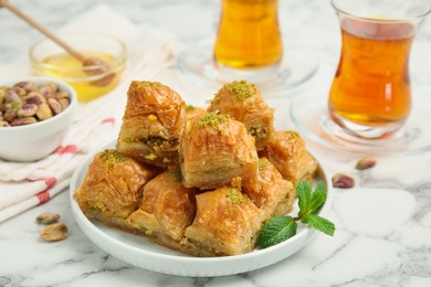 Photo of Delicious sweet baklava with mint on white marble table