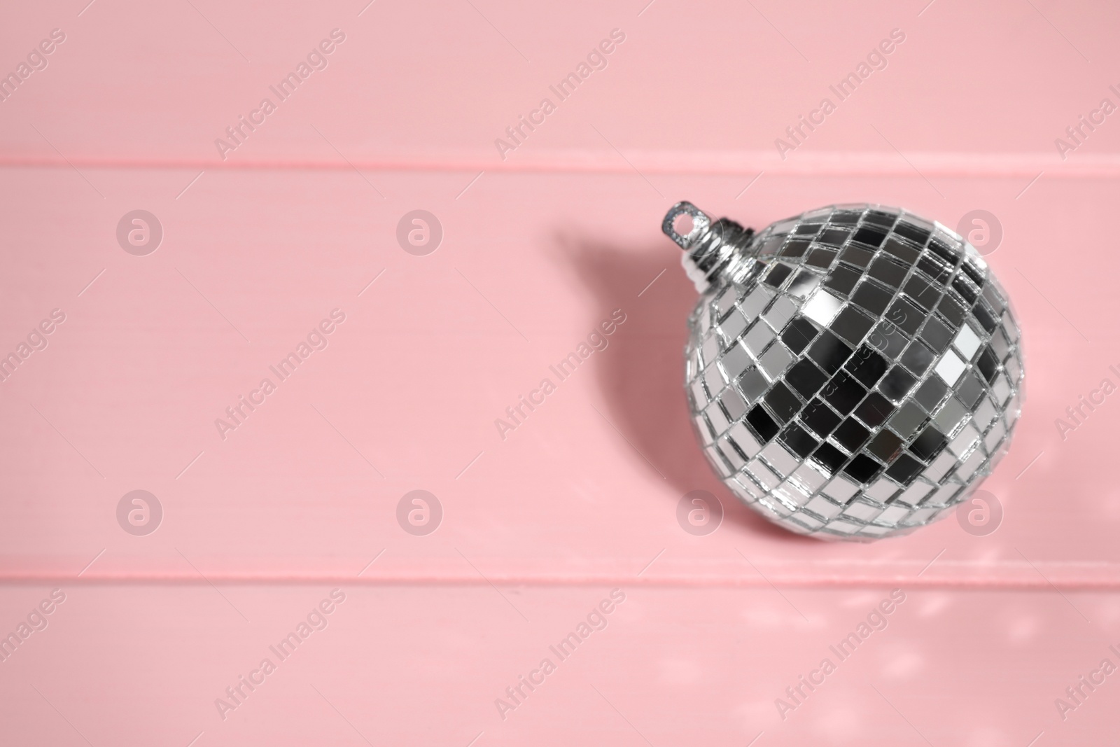 Photo of Shiny disco ball on pink wooden background, above view. Space for text