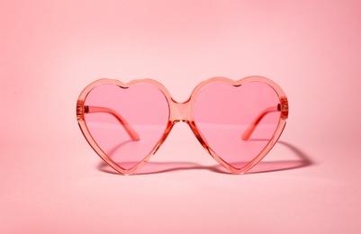 Photo of Stylish heart shaped glasses on color background