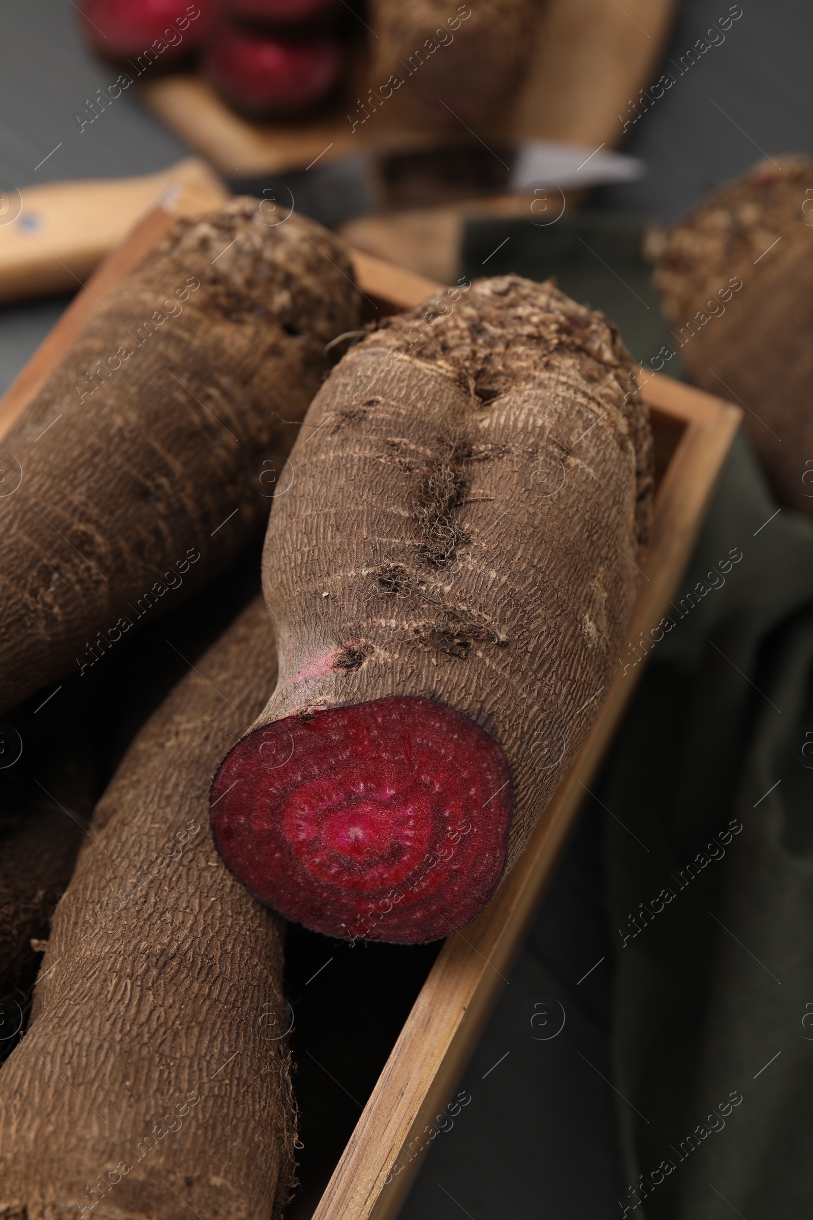 Photo of Whole and cut red beets in wooden crate, closeup