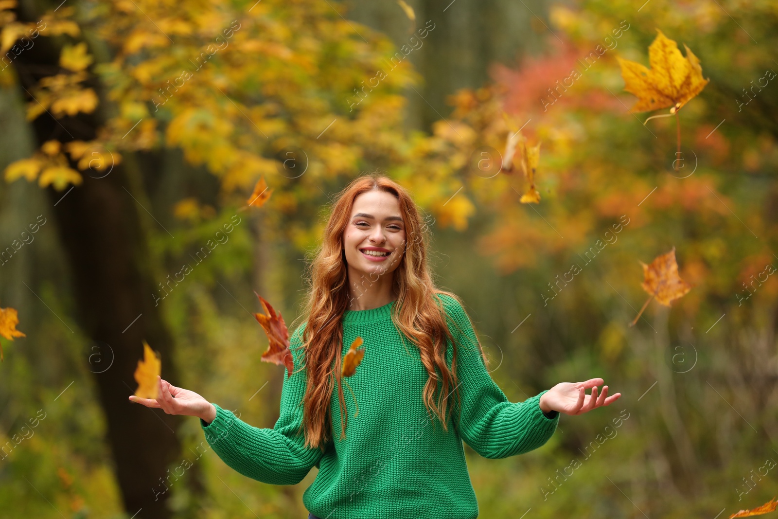 Photo of Autumn vibes. Happy woman throwing leaves up in park