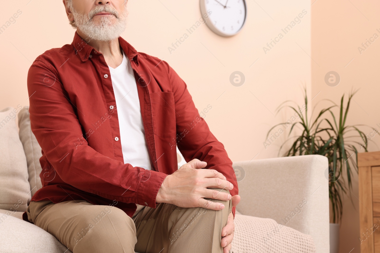 Photo of Senior man suffering from pain in his knee at home, closeup. Arthritis symptoms