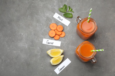 Photo of Flat lay composition with carrot juice and different ingredients on grey table, space for text