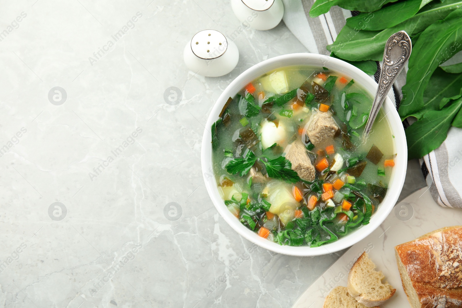 Photo of Delicious sorrel soup with meat served on marble table, flat lay. Space for text