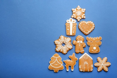 Photo of Christmas tree shape made of delicious gingerbread cookies on blue background, flat lay. Space for text