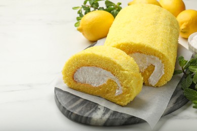Photo of Delicious cake roll, lemons and mint on white marble table, closeup. Space for text