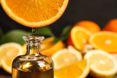 Photo of Citrus essential oil dripping from orange slice into bottle, closeup. Space for text