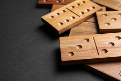 Photo of Wooden domino tiles on black background, closeup. Space for text
