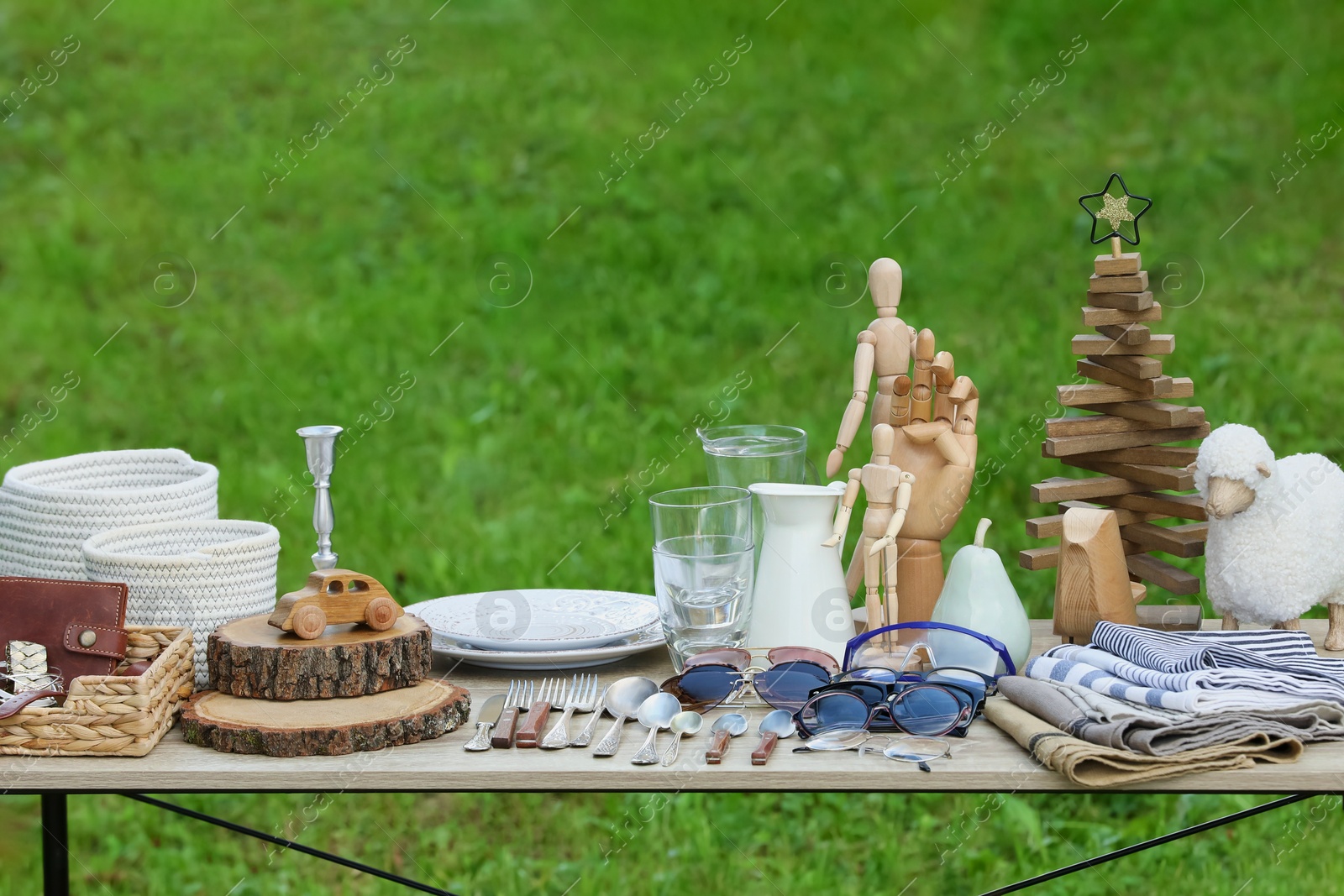 Photo of Many different decorative items on wooden table outdoors. Garage sale