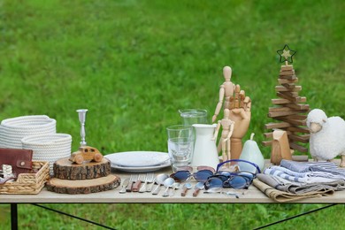 Many different decorative items on wooden table outdoors. Garage sale