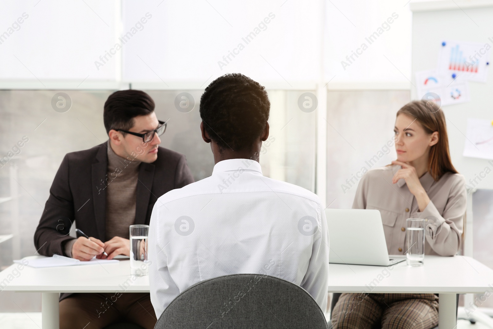 Photo of Coworkers conducting job interview with African American man in office, back view. Racism concept