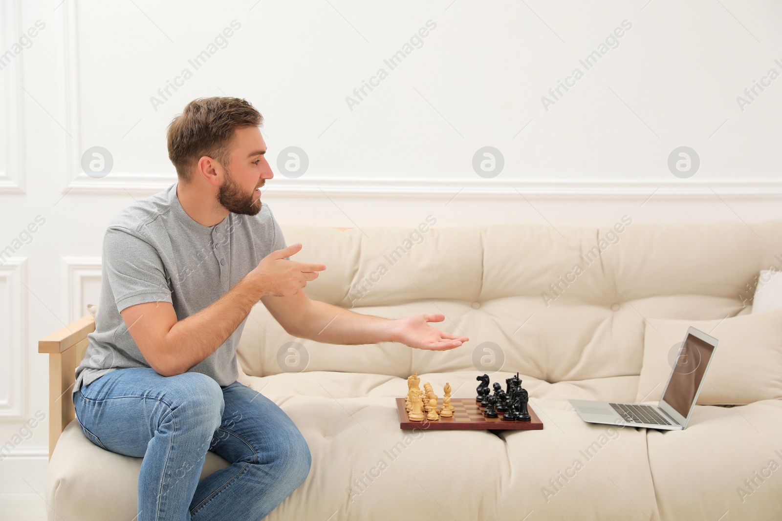 Photo of Young man playing chess with partner through online video chat at home