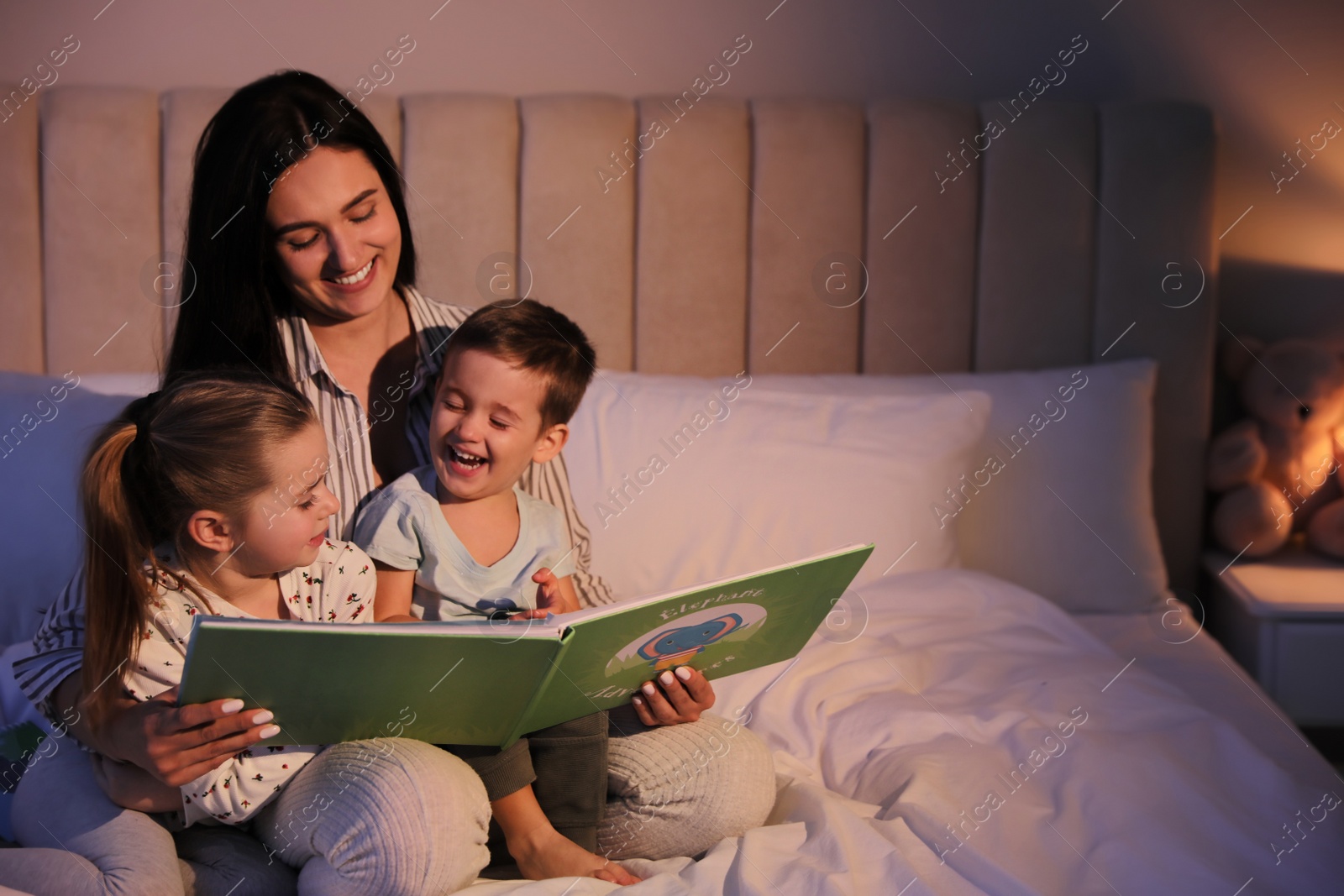 Photo of Mother reading bedtime story to her children at home