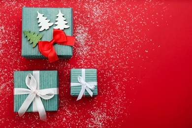 Christmas gift boxes with snow on red background, flat lay. Space for text