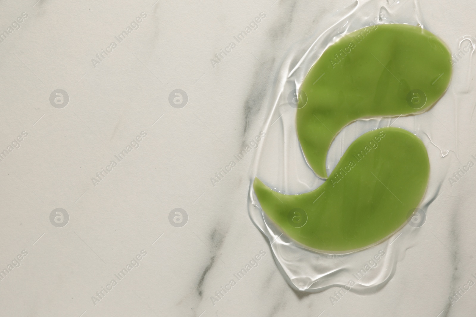 Photo of Green under eye patches with gel on white marble background, top view and space for text. Cosmetic product