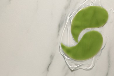 Photo of Green under eye patches with gel on white marble background, top view and space for text. Cosmetic product