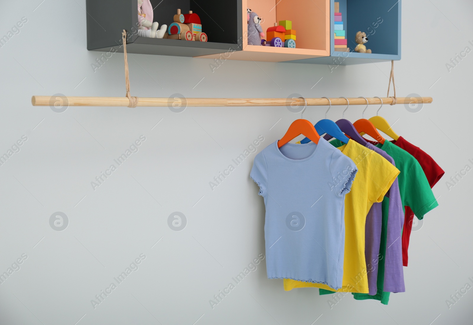 Photo of Rack with different clothes on light background