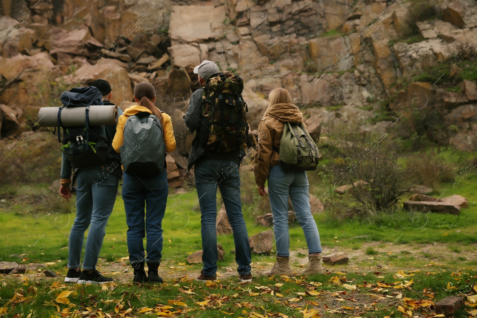 Photo of Group of hikers with backpacks in mountains, back view