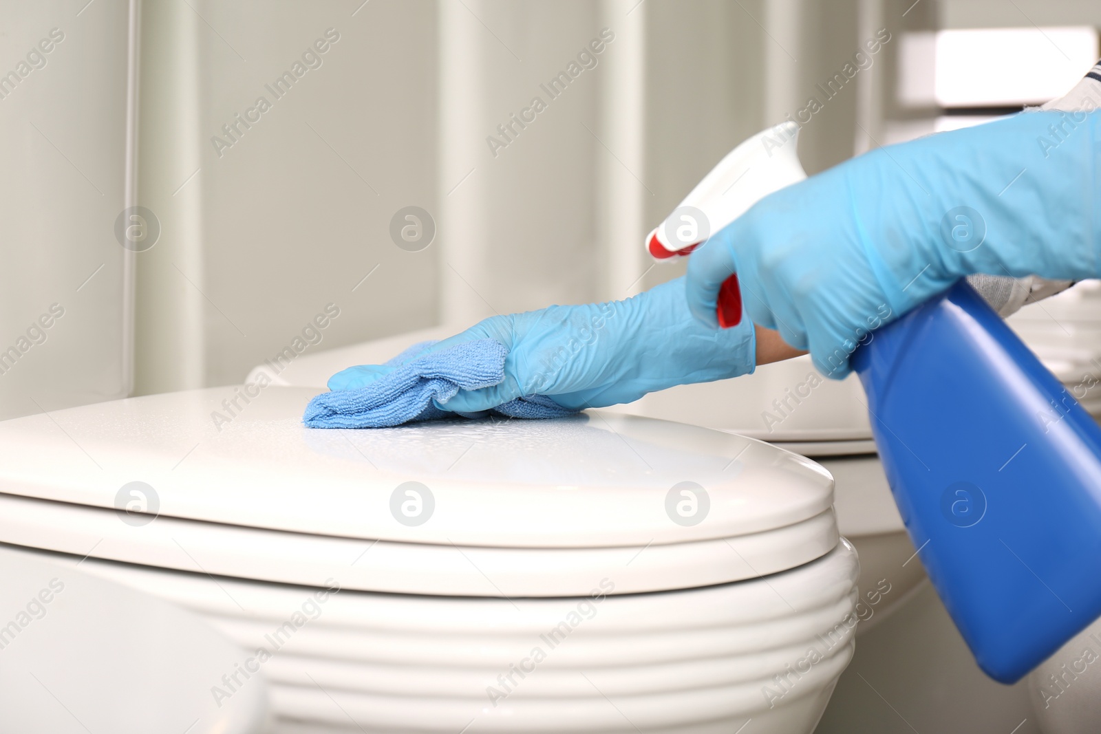 Photo of Woman cleaning toilet bowl with rag and detergent in 
store, closeup