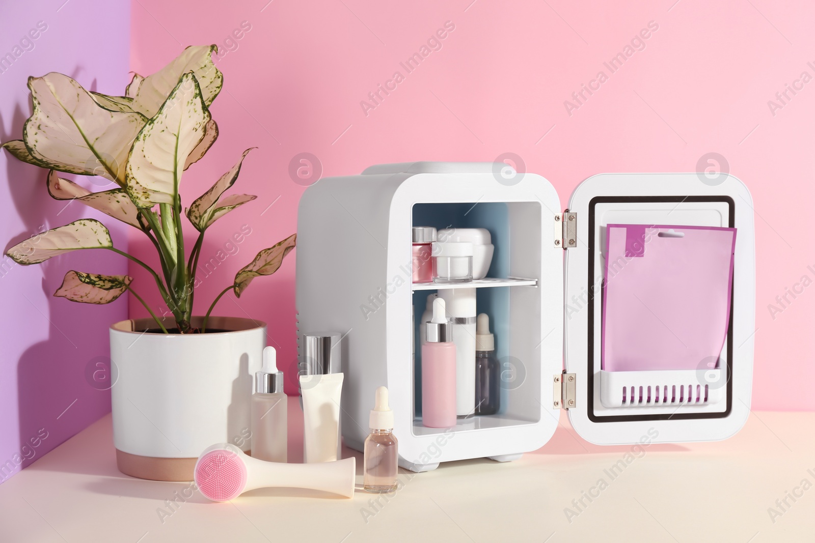 Photo of Open cosmetic refrigerator and skin care products on color background