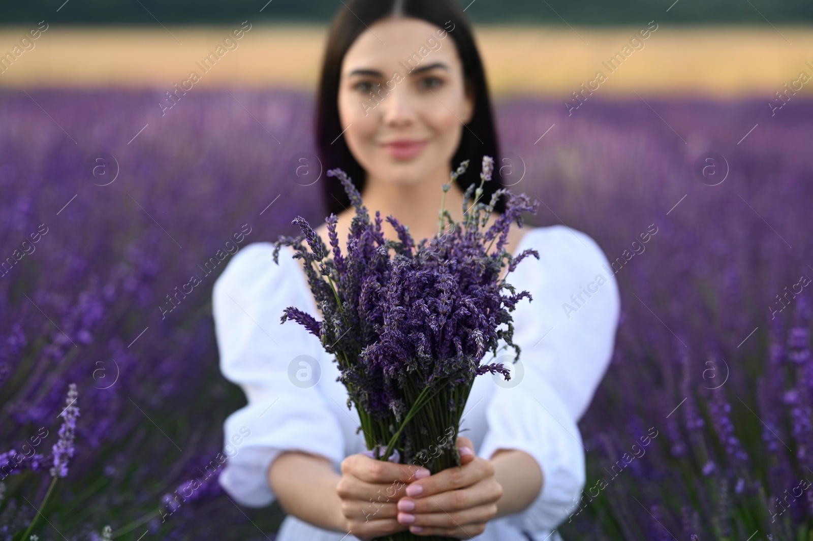 Photo of Beautiful young woman with bouquet in lavender field