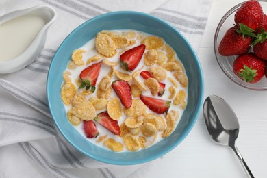 Bowl of tasty crispy corn flakes with milk and strawberries on white wooden table, flat lay
