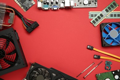 Frame of graphics card and other computer hardware on red background, flat lay. Space for text