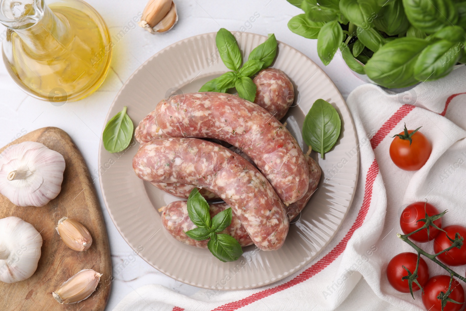 Photo of Raw homemade sausages and different products on white table, flat lay