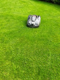 Photo of Modern robot lawn mower on green grass in garden