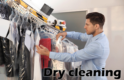 Image of Male worker taking clothes from garment conveyor at dry-cleaner's