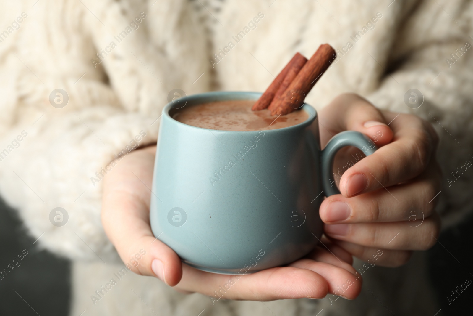 Photo of Woman holding cup of delicious hot cocoa with cinnamon, closeup