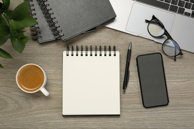 Photo of Flat lay composition with notebooks, laptop and smartphone on wooden table