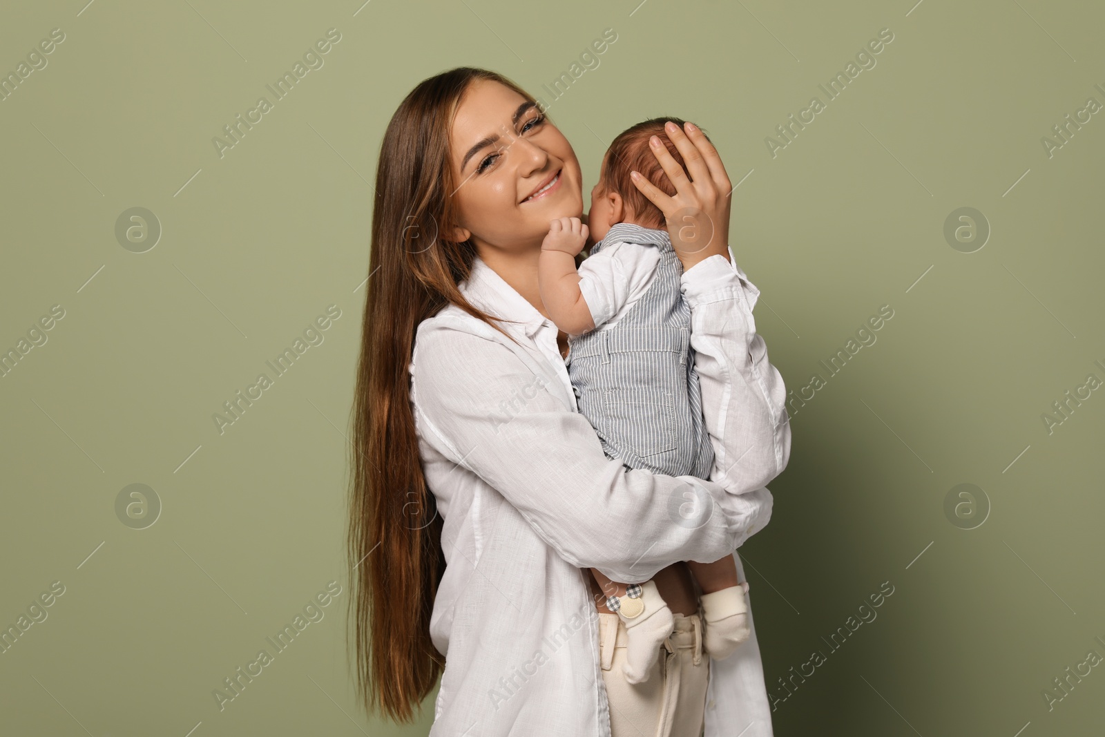 Photo of Mother holding her cute newborn baby on olive background