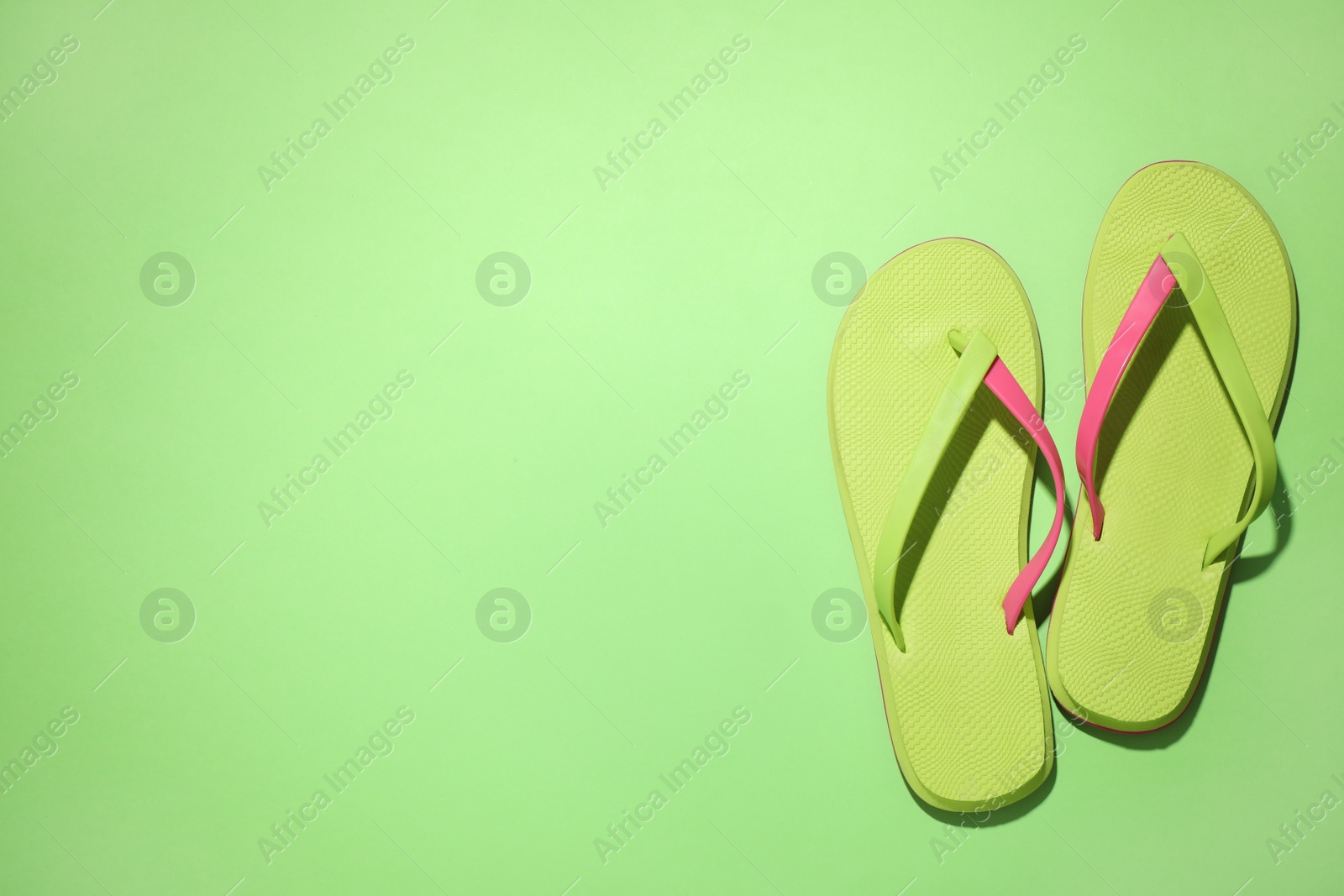 Photo of Pair of stylish flip flops on green background, top view with space for text. Beach objects