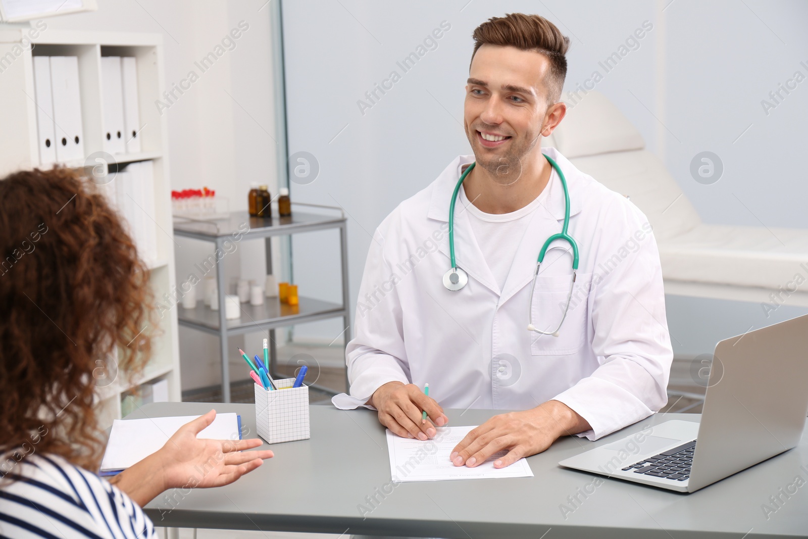 Photo of Male doctor working with African American patient in hospital