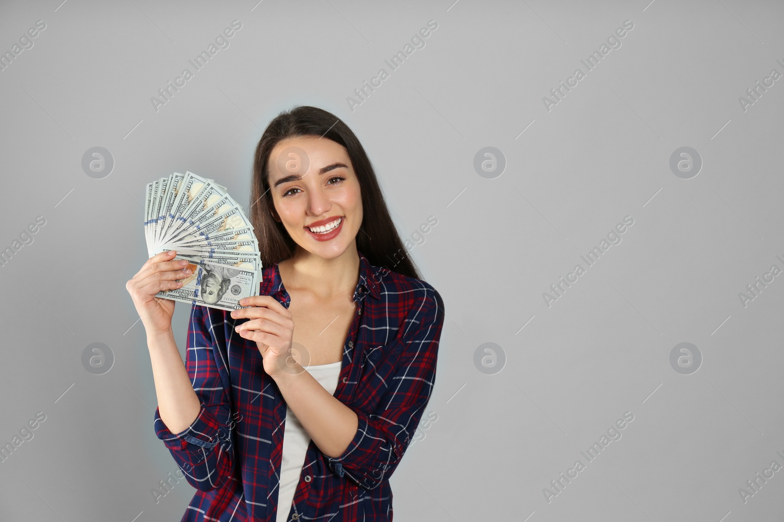 Photo of Young woman with money on light grey background. Space for text