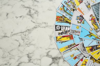 Photo of Tarot cards on white marble table, top view. Space for text