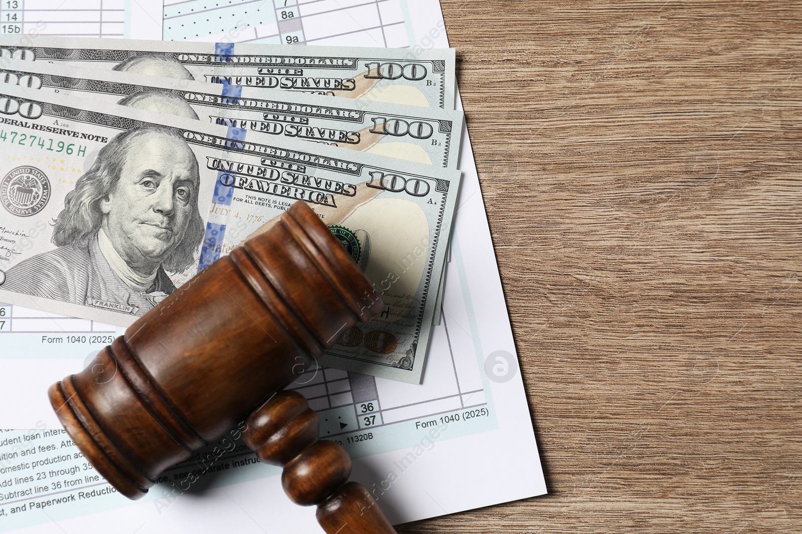 Photo of Tax return form, dollar banknotes and gavel on wooden table, top view. Space for text