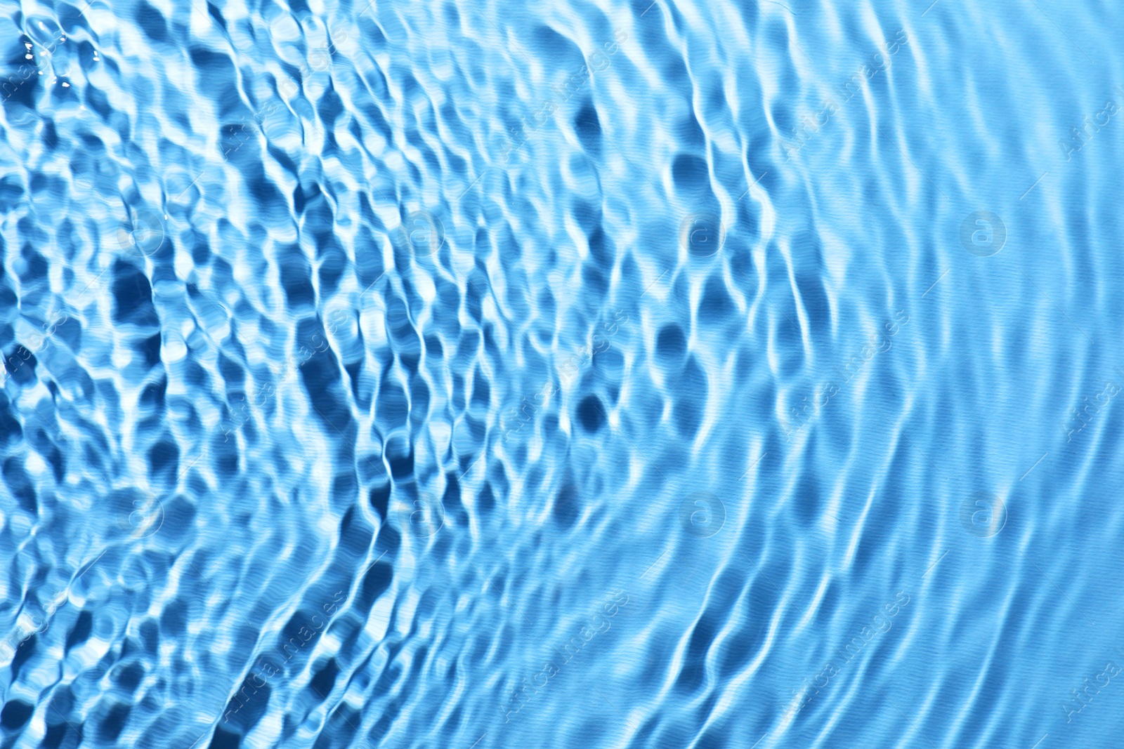 Image of Rippled surface of clear water on light blue background, closeup