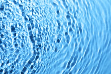 Rippled surface of clear water on light blue background, closeup
