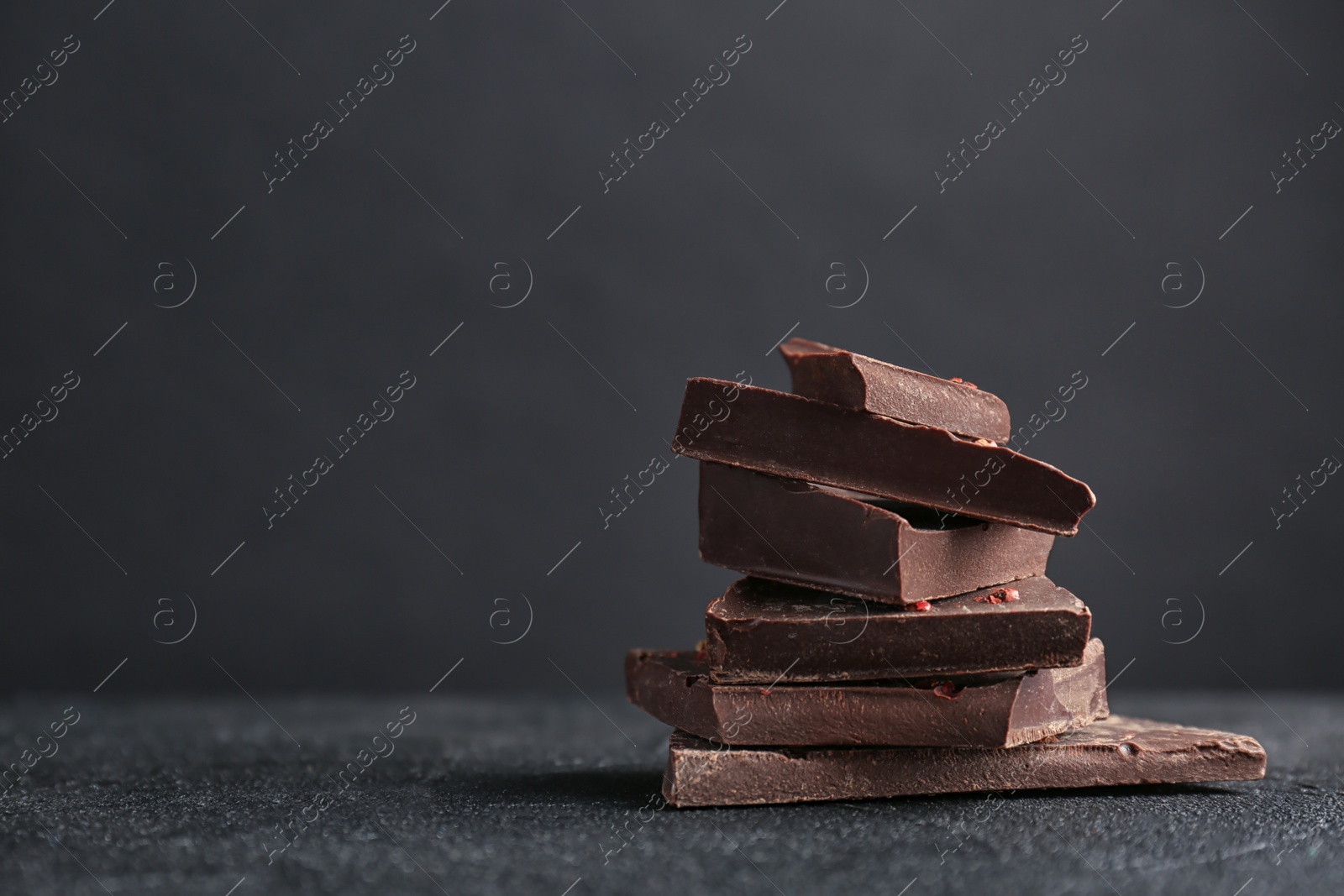 Photo of Pieces of delicious dark chocolate on table