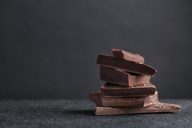 Photo of Pieces of delicious dark chocolate on table