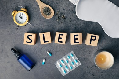 Photo of Flat lay composition with word Sleep made of wooden cubes and insomnia remedies on grey background