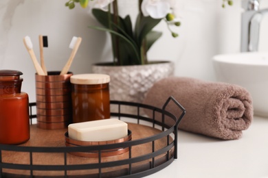 Photo of Tray with different toiletries and towel on countertop in bathroom, closeup