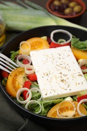 Bowl of tasty salad with leek and cheese on table, closeup