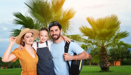 Portrait of happy family with child near palm trees outdoors