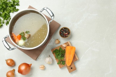 Photo of Pot with delicious bone broth and ingredients on light grey table, flat lay. Space for text
