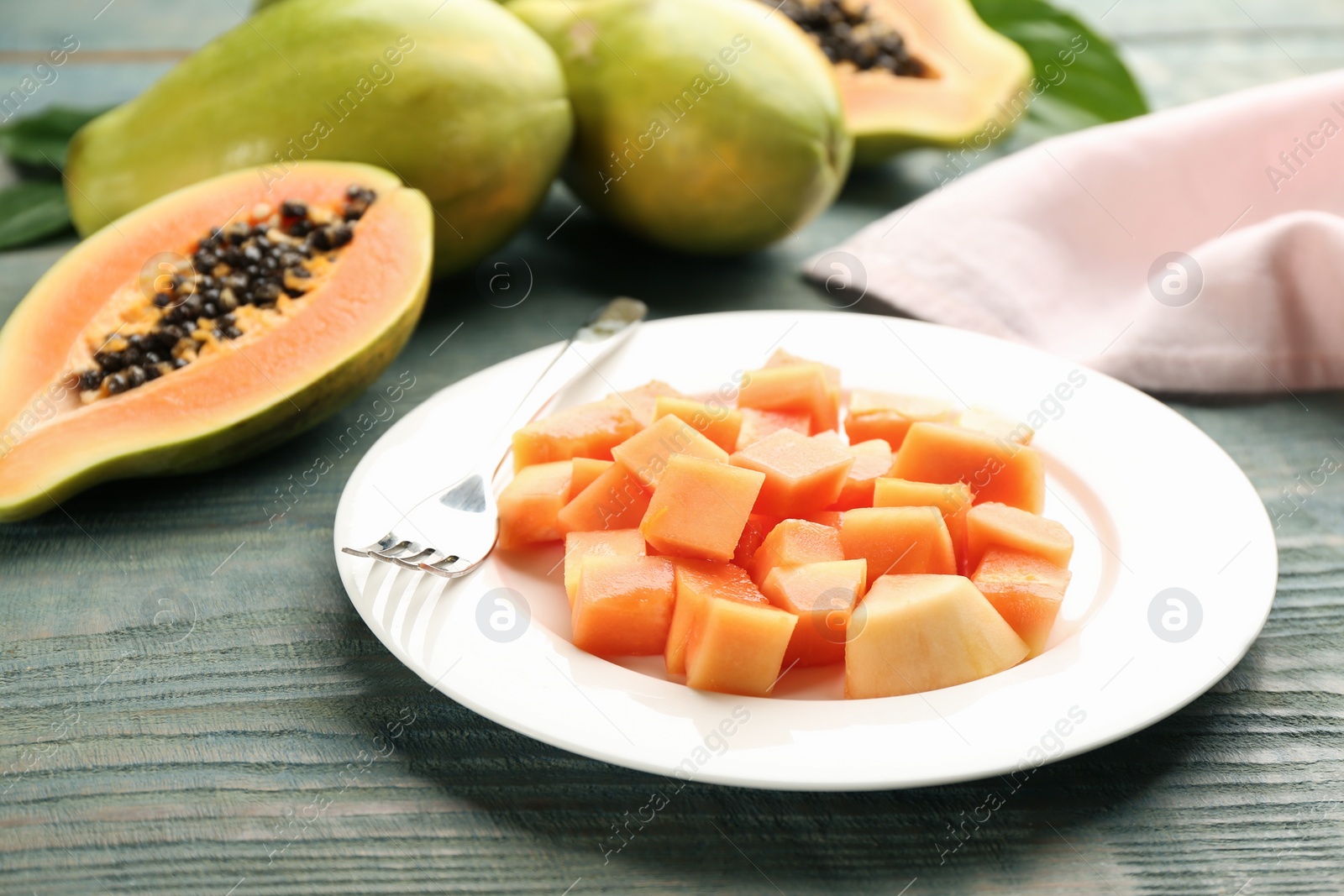Photo of Plate with diced papaya on wooden table