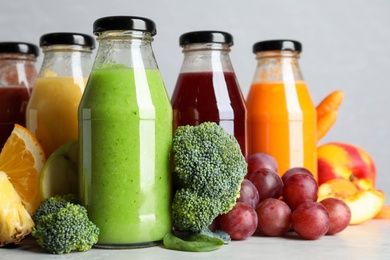 Bottles of delicious juices and fresh fruits on marble table