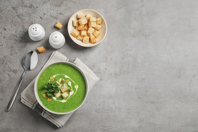 Photo of Tasty kale soup with croutons served on grey table, flat lay. Space for text